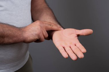 Beyaz bir arka planda bilek ağrısı tutan bir adam.