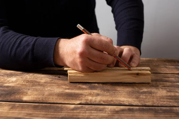 Erkek marangoz atölyesinde ahşap masada çalışıyor..