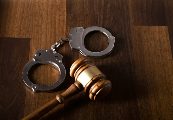 stock image judge gavel and handcuffs on wooden table. law