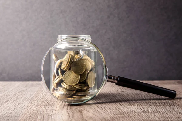 glass jar with coins and money on wooden table background