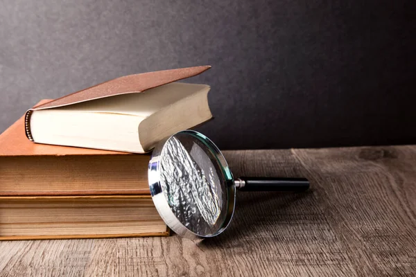 Büyüteç ve ahşap arka plan üzerinde kitap