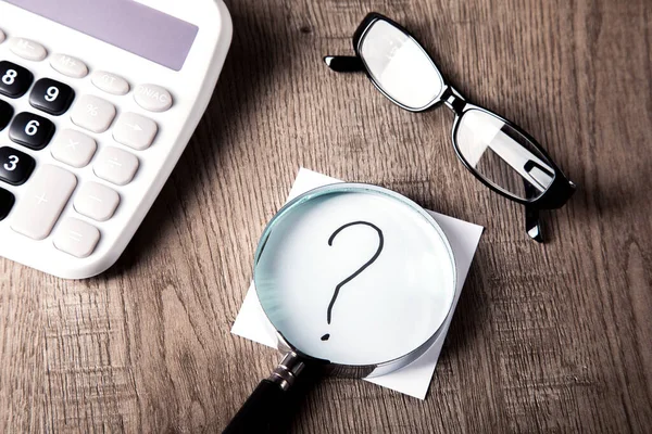 Bir soru işareti ile büyüteç, hesap makinesi ve soru işareti