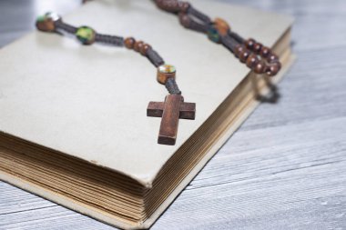 Ahşap masanın üstündeki eski kitaba çarmıhı kapat., 