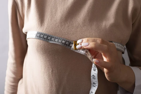 Bir kadın göğsünü bir mezura ile ölçüyor.