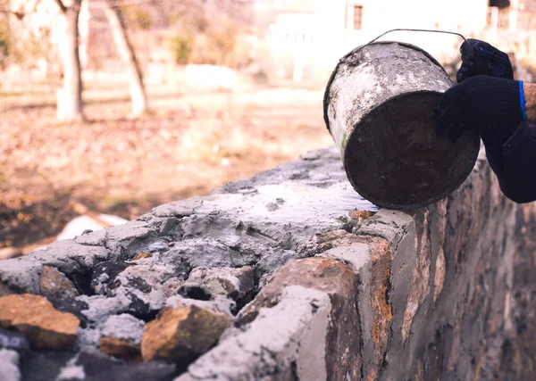 İnşaatçı bir kürek çimento fırlatıyor.