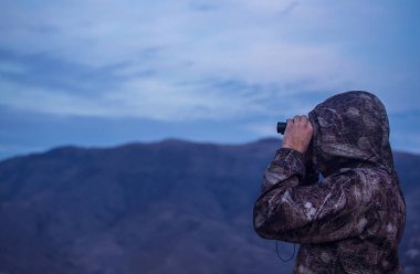 Dürbünle dışarı bakan bir adama yaklaş..
