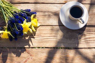 İlk bahar çiçekleri ve ahşap arka planda kahve.