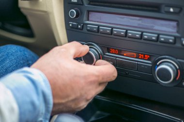Bir adam arabanın klima kontrol düğmesinin düğmesine basıyor.