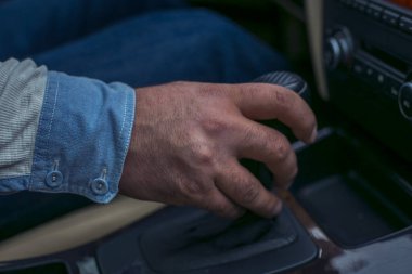  Araba kullanırken vites kolu tutan bir adam..