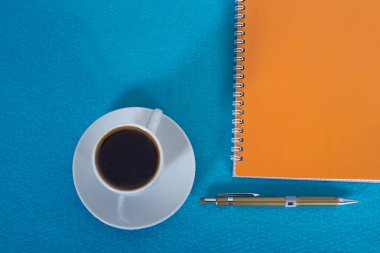 mavi arka planda defter, kalem ve kahve