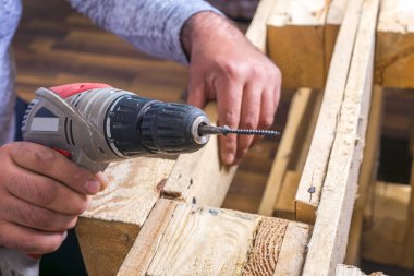 Marangoz kablosuz matkapla tahta bir plakayı düzüyor. 