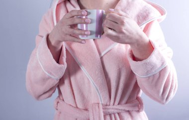 Bir fincan kahveyle bornozlu genç kız. 