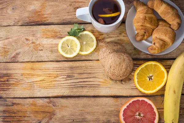 tasty breakfast with fruits and cup tea in wooden background