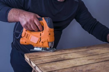 Ahşap işçiliği üzerine çalışan marangozun kapağı. Tahta yerine elektrikli yapboz kullanıyor.