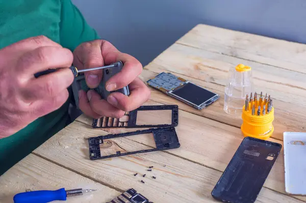 Cep telefonu tamiri, ahşap masaya yakın duran eller.