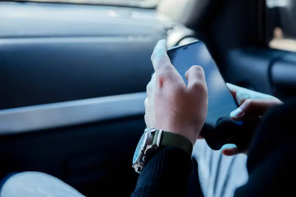 İş adamı arabada otururken akıllı telefon kullanıyor
