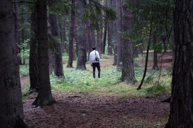 Ormanda siyah ceketli genç adam.