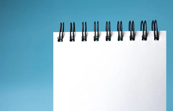 blank notepad with white blank paper on blue background. flat lay, top view