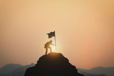 Gün batımında dağın zirvesine tırmanan insan ve insan silueti.