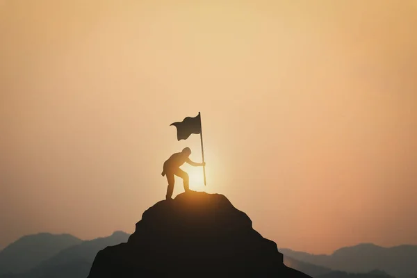 silhouette of man and man climbing mountain top on sunset time background