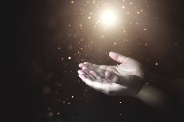 Yukarıdan parlayan ışıkla dua eden adamların elleri. Dua ve inanç kavramı, din ve inançla ilgili ruhanilik.