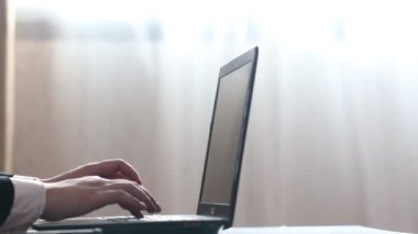 Dizüstü bilgisayar klavyesinde daktilo yazan bir iş adamının erkek eli ofis masasında oda penceresinden gelen ışıkla oturuyor. Pc uygulaması yazılım uygulaması teknoloji kavramı ile çevrimiçi çalış yan görünümü kapat