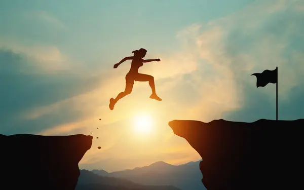 Çabalamak ve başarıya bağlılık. Parlak güneşli gökyüzü ile dağdaki bitiş çizgisine ulaşmak için uçurumdan atlayan bir kadının silueti. Zaferleriniz ve eğitiminiz için hedefler belirleme kavramı