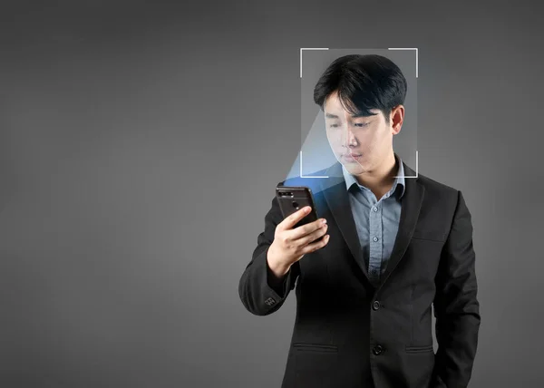 Businessman uses smartphone to scan face to unlock digital connection to access personal data. Modern technology security and protection with smartphone biometric facial recognition.