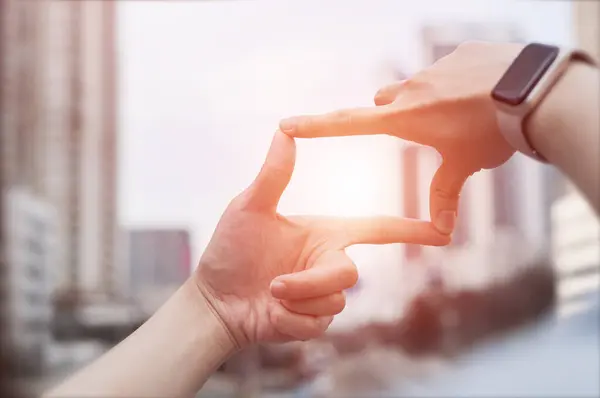 Businesswoman hand gesture focusing on search frame with tall buildings, business city area showing view of approaching target. Concept of vision and strategic planning