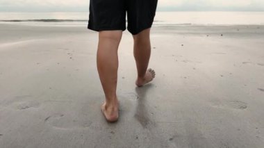 4K görüntüler, sabah sahilde yalın ayak yürüyen bir adamın ayakları. Chao Lao Plajı, Chanthaburi, Tayland 'da yaz tatili boyunca erkek turist
