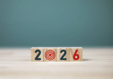 2026 iş büyümesi hedefi. Yeni yıl için iş stratejisi ve bütçe planlaması. 2026 yılı ahşap blokta mavi arkaplanda kopyalama alanı ile.