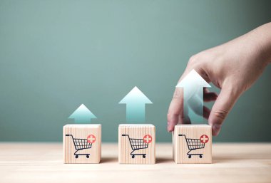 İş büyümesi kavramı, daha yüksek satış hacmi için pazarlama ve e-ticaret pazarlaması. Alışveriş arabası simgesiyle ahşap küp ve artan grafik.