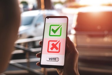 Akıllı telefon ekranında yeşil işaretli ve kırmızı çapraz simgeli bir oy başvurusu var. Seçim konsepti, siyasi seçim kampanyası oylaması ve demokratik sistemde hakların uygulanması sistemi