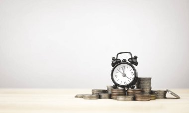 Kopya alanı olan bozuk paraların üzerindeki siyah çalar saat. Zaman yönetimi kavramları, finansal planlama, para biriktirmek için zaman ve geleceğe hazırlık için yatırım.