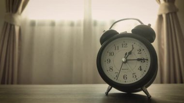 Siyah alarmlı saatin 4K Timelapse 'ı perde arkası ve yumuşak güneş ışığı, klasik tarzda. Zaman çabuk geçiyor, çalışma saatleri ve yönetim zamanı kavramı.