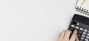 Hesaplamak için hesap makinesi kullanan bir adamın ellerinin üst görüntüsü ve beyaz masanın üzerindeki notlar. Para yönetimi kavramları, kayıt bütçeleri ve aylık harcamalar. kopyalama alanı ile