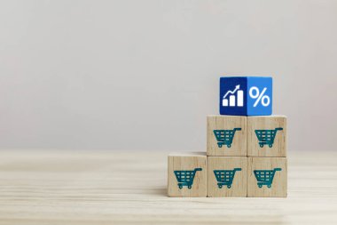 İş büyümesi kavramı, satış hacmini artırmak için pazarlama stratejileri ve e-ticaret. Alışveriş arabası simgesiyle ahşap küp ve artan grafik.