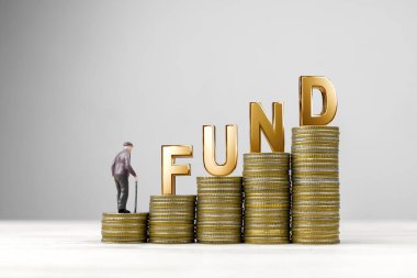 Bozuk para yığınının üzerinde kelime oyunuyla para taşıyan yaşlı bir erkek bebek. Mali planlama kavramı, Emeklilik Yatırım Fonu (RMF), kar payları ve mali risk yönetimi.