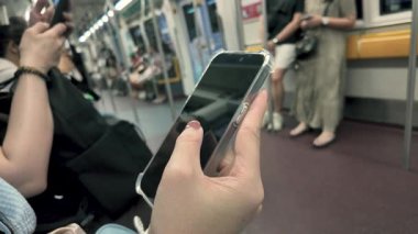 Metro yolcusu ve video, haberlerde parşömen ya da internet üzerinden bilgi arayan bir kadının elindeki akıllı telefonun yakın görüntüsü.