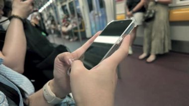 Metro yolcusu ve video, haberlerde parşömen ya da internet üzerinden bilgi arayan bir kadının elindeki akıllı telefonun yakın görüntüsü.