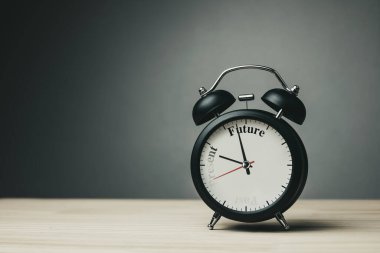 Saatin elleri simdiden geleceğe hareket eder, kelimeler siyah saat yüzünde kaybolurken. Olumlu düşünme, kişisel gelişim motivasyonu, iş planlaması ve gelecek eğilimleri kavramı.