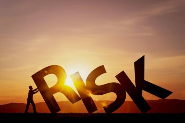 Gün batımına karşı RISK 'i zorlayan kişinin silueti. Riskleri önleme ve mevcut riskleri yönetme kavramları.