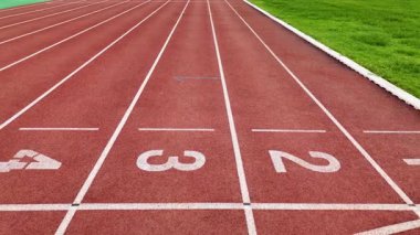 Açık havada numaralandırılmış başlangıç çizgileri olan kırmızı bir pistin görüntüsü.