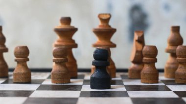 Kahverengi satranç taşı satranç tahtasında duruyor, arka planda diğer beyaz satranç taşları, oyun yarışması, politik strateji.