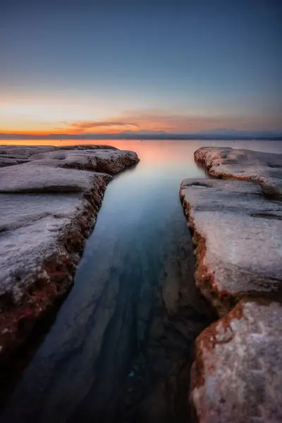 Gün batımında göl ve kayalarla güzel bir manzara. Garda Gölü, Sirmione, İtalya