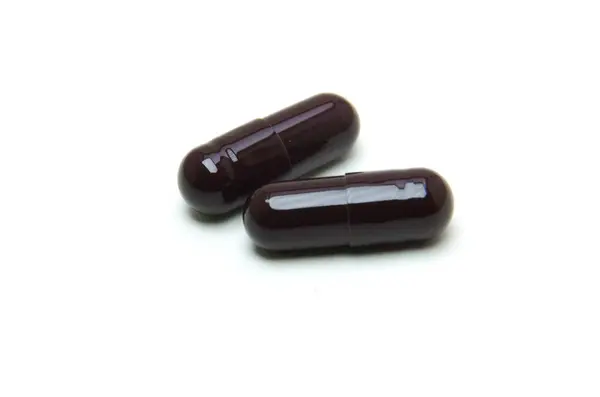 Beyaz arka planda izole edilmiş birkaç siyah hap.