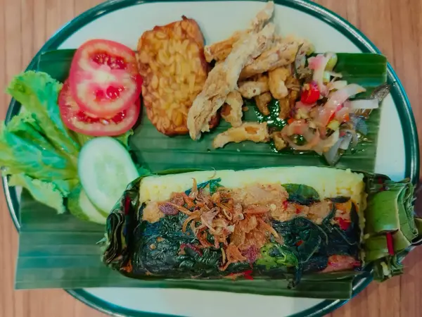 Vegan roasted rice is rice seasoned with vegan spices and side dishes, then wrapped in banana leaves. This version is specially served for those on a vegan diet. Roasted rice is a traditional Indonesian food.