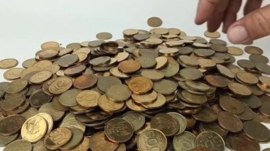 A man's hand takes coin from a pile of coins on the table. Coins with a denomination of 500 rupiah.