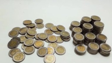 A man's hand takes coin from a pile of coins on the table. Coins with a denomination of 500 rupiah.