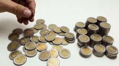 A man's hand takes coin from a pile of coins on the table. Coins with a denomination of 500 rupiah.